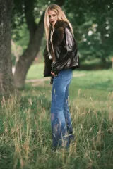 Jeans de denim azul oscuro con efecto lavado y desgaste sutil en la parte delantera de los muslos y las rodillas. Diseño de tiro alto, cinco bolsillos y corte acampanado desde la rodilla hacia el bajo.