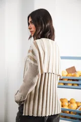 Buzo color beige con rayas horizontales en lurex dorado, cuello con medio cierre, corte oversized y logo tejido en el puño.