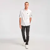 Camisa de popelina verde con cuello abotonado, cierre frontal con botones, bolsillo de parche en el pecho izquierdo, mangas largas con trabillas para enrollar y dobladillo camisero.