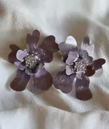 Par de aros con forma de flor color lila con centro de strass plateado.