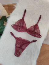 Conjunto de lencería de encaje color bordó, compuesto por un corpiño triangular sin aro y una bombacha less con tiras finas.