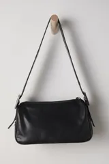Bolso bandolera color crema, de cuero, con correa ancha ajustable con hebilla dorada.