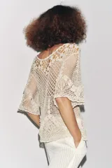 Top de crochet color crema, con cuello redondo y mangas cortas.
