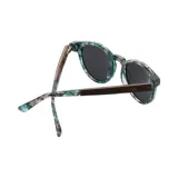Lentes de sol redondos con montura de acetato con estampado de hojas en tonos verdes y grises. Lentes grises y patillas con el logo de la marca Indie. Hechos a mano y sustentables.