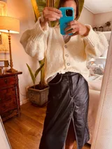 Pollera midi de cuero negro con abertura frontal y costuras blancas a contraste.