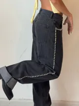 Pantalón de jean gris oscuro con corte recto y detalles de tachas plateadas en los laterales.