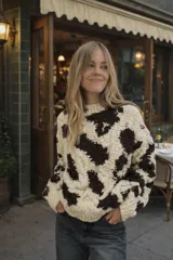 Sweater de lana merino color crema con cuello alto y diseño con motivos geométricos en amarillo, naranja, violeta y negro.