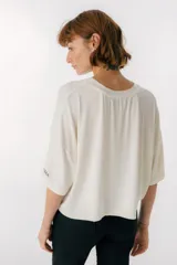 Remera color crema de corte cuadrado y mangas cortas.