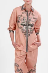 Camisa de popelina color rosa con estampado de paisajes italianos en blanco y negro. Tiene cuello clásico, mangas largas con puños abotonados y cierre frontal con botones.
