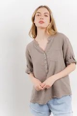 Camisa azul de lino con escote en V abotonado, bolsillo frontal y mangas 3/4 con trabilla.