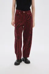 Pantalón de jean de tiro alto con estampado animal print de cebra en tonos borgoña y negro.