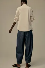 Camisa color crema de hilatura con algodón y lyocell, con cuello solapa, manga larga acabada en puño y bolsillo de plastrón en el delantero.