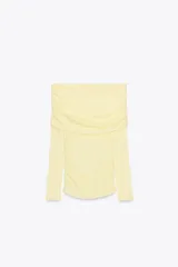 Camiseta amarilla de algodón con escote recto, hombros descubiertos y mangas largas. Presenta detalle de frunces en el cuerpo.