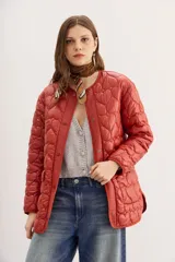 Campera color ladrillo con matelassé de corazones, corte amplio, mangas largas y bolsillos con solapa y botones snap en el frente.