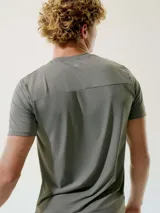 Remera deportiva verde con cuello redondo y mangas cortas. Presenta detalles reflectantes en los hombros.