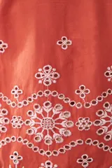 Remera color ladrillo con bordado de flores blancas en el ruedo y las mangas.