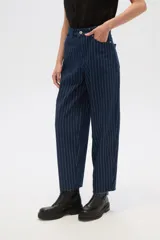 Pantalón de jean azul con finas rayas verticales blancas, de tiro alto, corte recto y terminación desflecada en el ruedo.