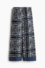 Pantalón de lino liviano con estampado paisley en tonos azul y blanco. Modelo de corte holgado con cintura elástica de tiro alto, bolsillos laterales discretos y piernas amplias.