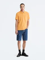 Chomba color naranja de manga corta, con cuello polo y tapeta de dos botones. Tiene el logo de Calvin Klein bordado en el pecho. Corte regular.
