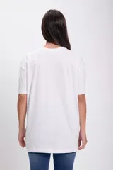 Remera blanca de corte oversize con estampado de flores color naranja y texto.