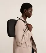 Cartera tipo baguette color negro, confeccionada en material sintético con textura en relieve. Tiene correa de hombro ajustable y cierre de cremallera.