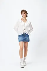 Minifalda de jean celeste con tiro bajo y detalle de tachas metálicas en los bolsillos.