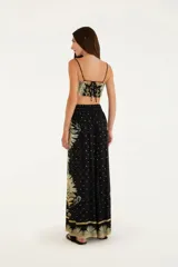 Pantalón recto de viscosa con estampado floral en tonos beige y celeste sobre fondo negro. Tiene cintura alta y corte clásico.