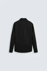 Sobrecamisa negra de tejido con elasticidad, cuello solapa, manga larga con puño abotonado, bolsillos de plastrón en el pecho y cierre frontal con botones a presión.
