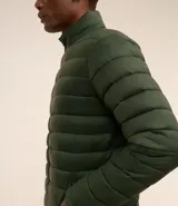Campera puffer ultraligera color beige, con cuello alto, cierre por cremallera y bolsillos con cremallera. Incluye bolso de almacenamiento.