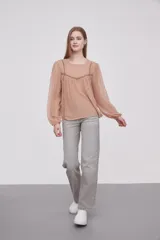 Blusa color beige oscuro con textura de lunares, cuello redondo y mangas largas abullonadas.