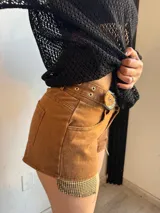 Short de jean color marrón con detalles de tela escocesa en los laterales y cinturón con hebilla metálica.