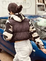 Campera puffer cropped negra con mangas y capucha de polar estampado con diseño geométrico en tonos beige, marrón y negro.