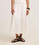 Pollera midi de corte evasé confeccionada en sarga de algodón blanco. Presenta un diseño con recortes verticales y nesgas que aportan volumen en el ruedo, cintura ajustada y largo por debajo de la rodilla.