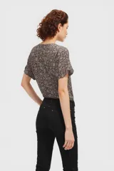 Blusa marrón con estampado floral en tonos beige, corte recto, cuello redondo y mangas cortas.