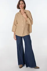 Camisa de lino color blanco, de manga larga y corte holgado, con cuello camisero y cierre frontal de botones.