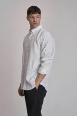 Camisa blanca de lino con cuello abotonado, manga larga con puños abotonados y corte clásico.