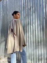Capa color beige de tejido de punto en lana con apliques en cuero y diseño asimétrico.