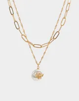 Collar corto dorado de doble cadena, una de eslabones grandes y otra de eslabones finos, con dije de perla irregular y ángel dorado.
