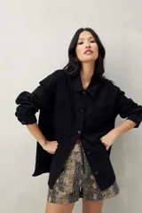 Sobrecamisa oversize de jean azul con cuello camisero, cierre frontal con botones, mangas largas y bolsillos de parche en el pecho.