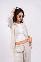 Camisa a rayas verticales color beige y blanco, con cuello clásico, cierre frontal con botones y mangas largas.