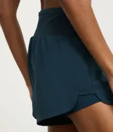 Bermuda deportiva femenina de microfibra color amarillo claro, con diseño de doble capa: un short interno ajustado y una capa externa suelta con bajo redondeado. Posee cintura alta.