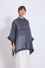 Camisa blanca de lino con cuello clásico, cierre frontal con botones, mangas anchas 3/4 y detalles de bordado calado en el canesú y los puños.