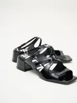 Sandalias negras de cuero charol con correa ajustable en el tobillo y taco cuadrado de 4,5 cm.