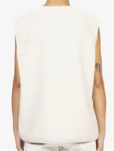 Chaleco oversize confeccionado en tejido teddy color beige. Presenta cuello en V, cierre frontal con botones a contraste y bolsillos laterales aplicados.