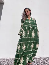 Vestido largo tipo túnica color verde con estampado beige, cuello en V y mangas largas.