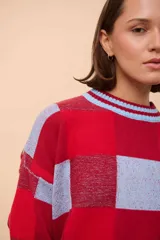 Sweater de punto con diseño a cuadros rojos y celestes, de corte holgado y cuello redondo.