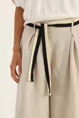 Pantalón ancho de lino color beige con cinto blanco y negro.