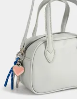 Cartera bowling color gris claro de cuerina con doble asa corta de mano, correa regulable y cierre superior.