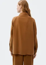 Camisa color marrón con cuello clásico, cierre frontal con botones, mangas largas y dos bolsillos de parche en el pecho.