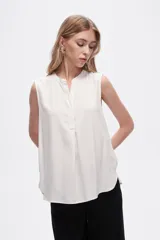 Blusa viscosa color negro, corte evasé, sin mangas, con cuello a la base y botón en la parte superior.